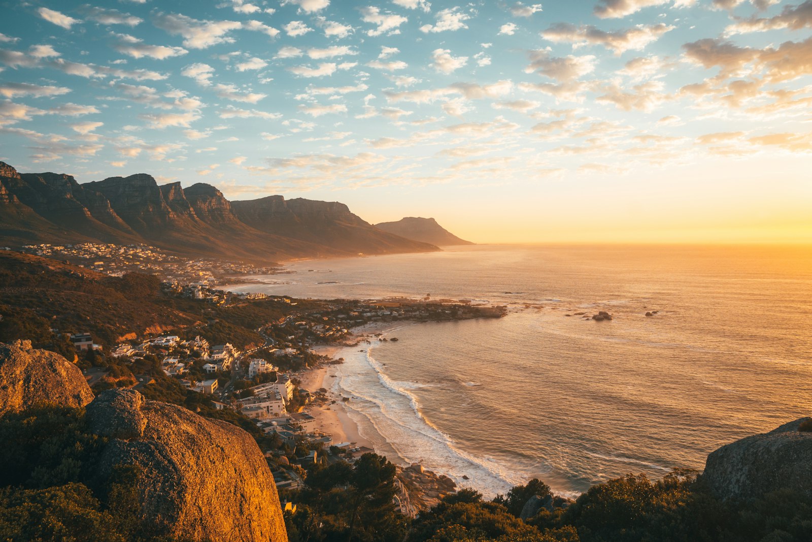 The Cape coastline glowing at golden hour, a small town nestled beneath the mountains beside the Atlantic